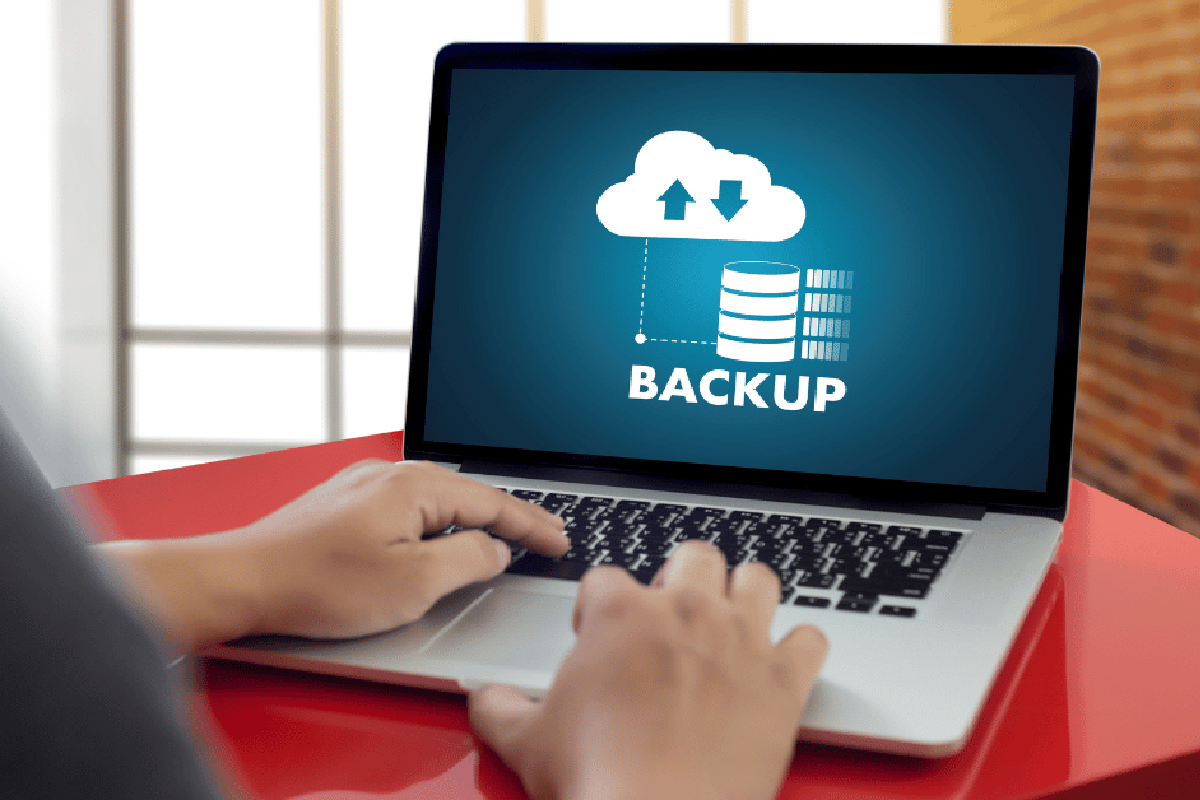 An image of a person connecting an external drive to a laptop, emphasizing the importance of data backup.